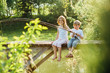 © Iryna - Barefoot boy and girl sitting on wooden pier with rod. Love, friendship concept. Beautiful romantic sunset picture.