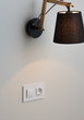 © Bakulov - White European electrical socket and switch on the gray wall. Stylish modern black lamp