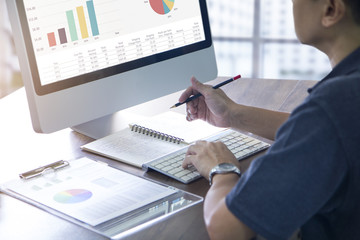 Wall Mural - Businessman in casual costume working in front of computer analysing business performance or return on investment.