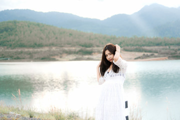 Portrait of happy smiling asian woman wear white dress standing at lake on sunny summer day.