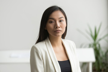 Confident attractive asian businesswoman looking at camera, ambitious serious chinese businesslady posing in office, successful young independent woman business owner head shot portrait