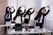 © Andrey Popov - Businesspeople Doing Exercise Behind Desk