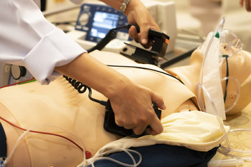 A white coat physician perform defibrillationon a doll during ACLS training program