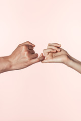 Wall Mural - cropped image of woman and man crossing little fingers isolated on pink background