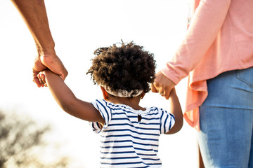 Little girl holding hands with her parents.