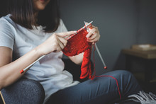 Close Up Shot Of Young Woman Hands Knitting A Red Scarf Handicraft In The Living Room On Terrace At Home