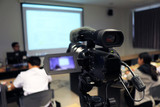 Fototapeta  - Photographer recording  video lecturer and student learning in classroom of university. - Education or seminar concept selective focus on video camera.
