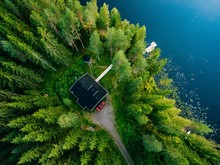 Aerial View Of Wooden Cottage In Green Forest By The Blue Lake In Rural Summer Finland