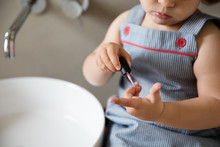 Close Up Of Toddler Painting Nails In Bathroom