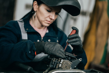 Wall Mural - Strong and worthy woman doing hard job in car and motorcycle repair shop.