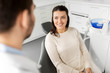 medicine, dentistry and healthcare concept - smiling female patient talking to dentist at dental clinic office