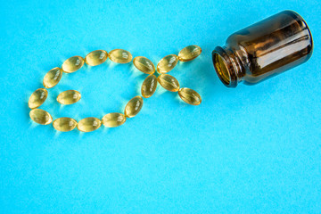 Wall Mural - Fish oil capsules on blue background, fish shape