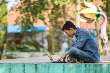 Asian young  man using computer outdoor