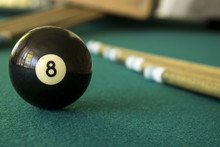 Eight Black Ball On A Green Table With Cue Sticks