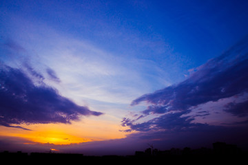 Wall Mural - atmospheric blue cloudy sky behind silhouettes of city buildings. purple and orange background of su