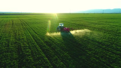 Fototapete - Aerial view of farming tractor plowing and spraying on field