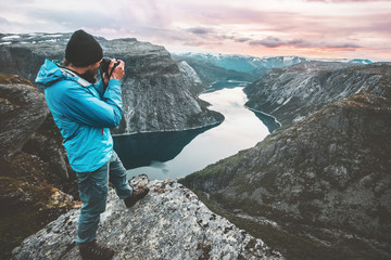 Wall Mural - Man travel photographer taking photo landscape in Norway mountains standing on cliff hobby lifestyle adventure vacations lake aerial view