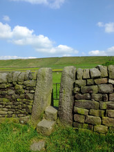 A Dry Stone Wall With Stone Stile Or Narrow Gate With Steps In A Yorkshire Dales Hillside Meadow With A Bright Blue Summer Sky And Sunlit Grass