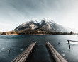 © Hofschulz & Schoppa - Gefrorener See im Spätwinter in den Alpen mit blick auf gewaltiges Bergmassiv und kleinem Holzsteg im vordergrund im Bild Hintersee und Watzmann