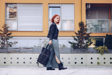 street style portrait of an attractive woman wearing a long dress, biker ankle boots and a big black leather tote bag . fashion outfit 