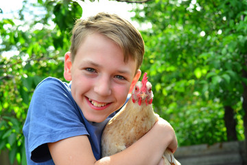 The boy is holding a white chicken and smiling