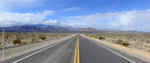 Cuadros en Lienzo Driving on the open road in the desert with mountain backdrop