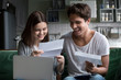 Happy young couple excited by reading good news in paper letter about refund tax money, millennial man and woman glad to receive special offer about cheap deal, test results or invitation by mail