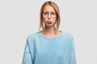 Image of affronted beautiful female curves lower lip and looks stressfully, has miserable expression, wears blue sweater, has some problems with her personal life. People, negative facial expressions