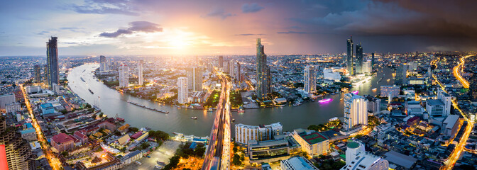 Fototapete - Aerial view of Bangkok skyline and skyscraper with light trails on Sathorn Road center of business in Bangkok downtown. Panorama of Taksin Bridge over Chao Phraya River Bangkok Thailand at sunset.