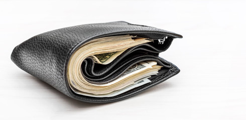 Full wallet with money on white wooden background.