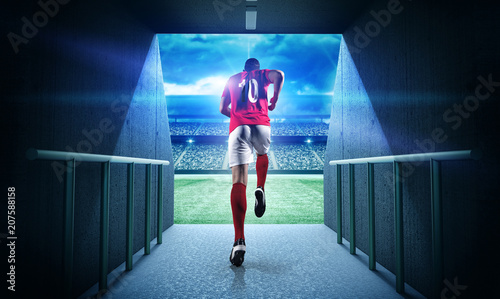 Fototapeta na szkło Piłkarz wchodzący na wyobrażony stadion 3d