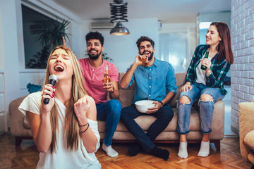 Wall Mural - Group of friends playing karaoke at home. Concept about friendship, home entertainment and people