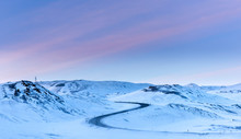 Winding Road In Snow Covered Mountains At Sunset