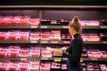 Woman Purchasing A Packet Of Meat At The Supermarket