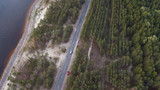 Fototapeta Na ścianę - Aerial view of winding road along coastline through lush green forest