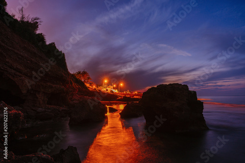 Fotografie, Obraz Sunset on the beach among the rocks near the city of Denia