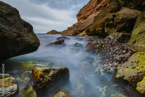 Fotografie, Obraz Sunset on the beach among the rocks near the city of Denia