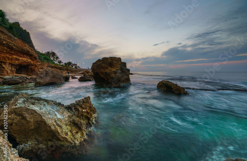 Fotografie, Obraz Sunset on the beach among the rocks near the city of Denia