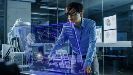 Wall Mural - Asian Neural Microchip Design Engineer Uses Modern Computer With Transparent Holographic Display. Monitor Shows Advanced Technology Interface. Shot in Modern Glass and Concrete Office.