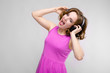 © Ivan Traimak - Charming young girl in pink dress on gray background. Young girl with headphones smiling