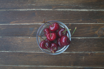 cherries inside transparent bowl on a wooden table top view