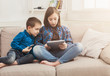 © Prostock-studio - Two kids with gadgets on couch at home