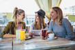 © Mediteraneo - Female friends enjoying in conversation and drinking coffee in cafe and using digital tablet.