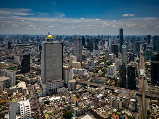 Wall Mural - Aerial view of Bangkok skyline and skyscraper with BTS skytrain Bangkok downtown. Panorama of Sathorn and Silom business district Bangkok Thailand with blue sky and clouds.