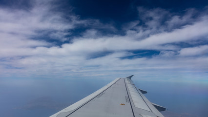 Plane wing on blue cloudy sky background