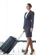 © pressmaster - Young businesswoman in suit and high-heeled shoes pushing suitcase in front of herself while walking down airport
