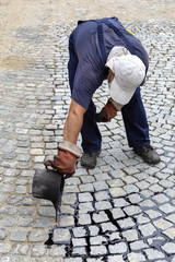 Wall Mural - Worker pouring molten pitch from a tar bucket