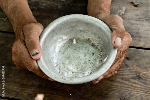 Fotografía The poor old man's hands hold an empty bowl of beg you for help