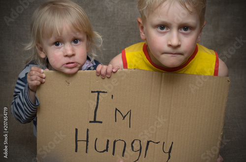 Fotomural A hungry boy and a girl with a cardboard tablet with the inscription I'm hungry