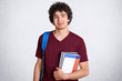 © sementsova321 - Positive young male teenager with pleasant charming smile, holds books, carries bag, prepares for classes at college, likes studying and find out something new, isolated on white background.